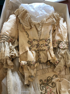 Elaborate ivory court gown with lace and embroidery in a large box with tissue paper