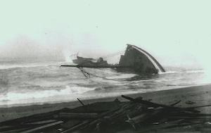 A shipwreck in the water with timber planks washed up on the beach