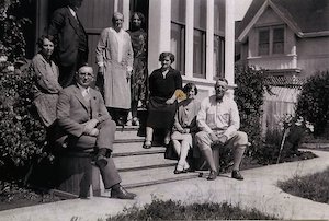 Members of an extended family posing around the front steps of a home