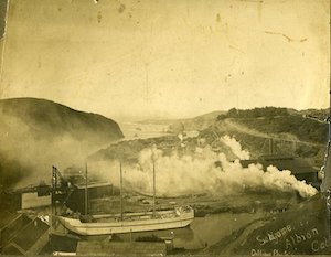 A large ship in front of a building with hills in the background