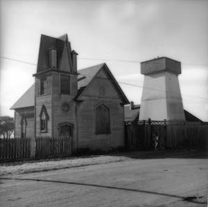 A wooden church behind a fence next to a water tower