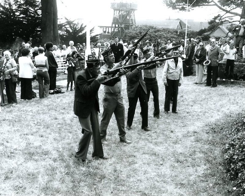 Four uniformed men firing rifles