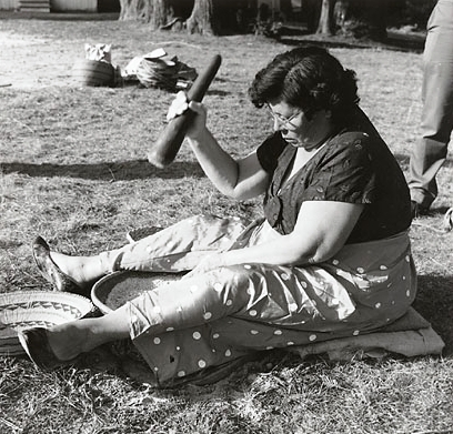 Woman on ground with mortar and pestle
