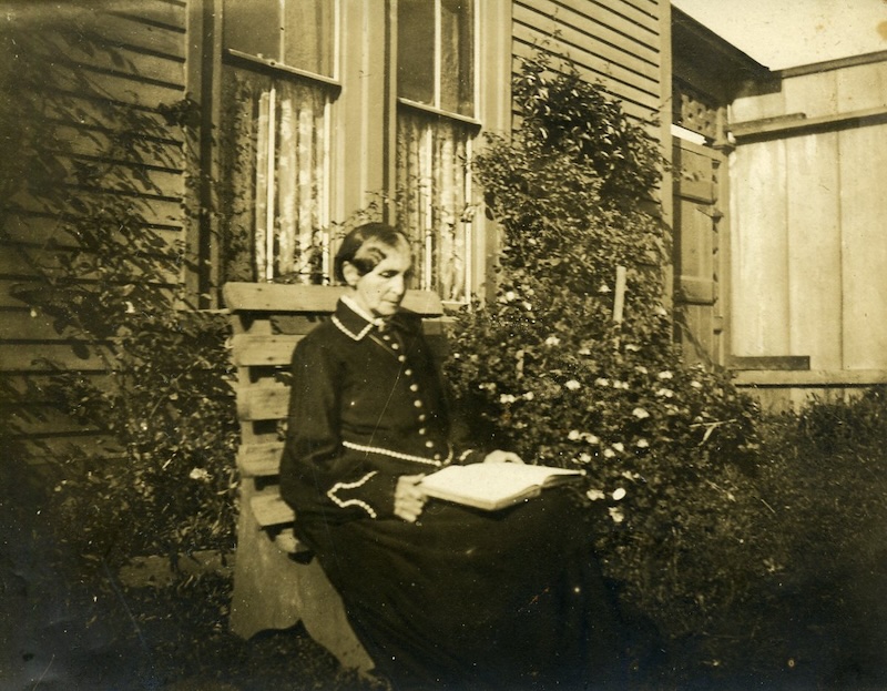 Woman reading book on garden bench