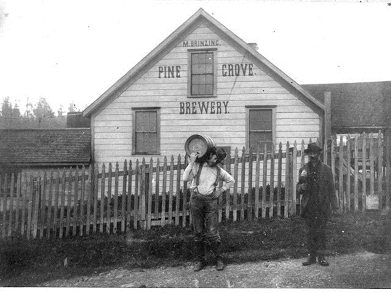 Two men stand in front of brewery building