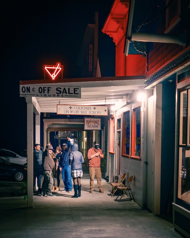 Crowd standing in front of bar under neon martini sign