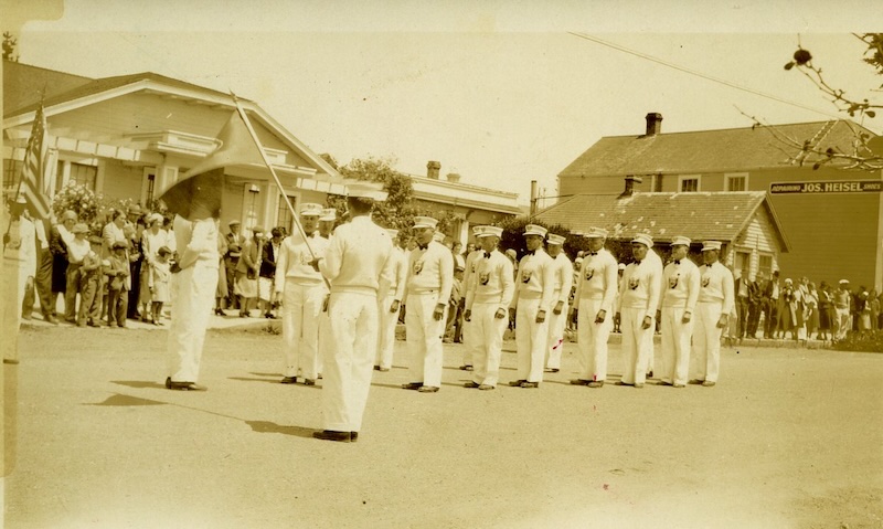 Group of uniformed man marching down street